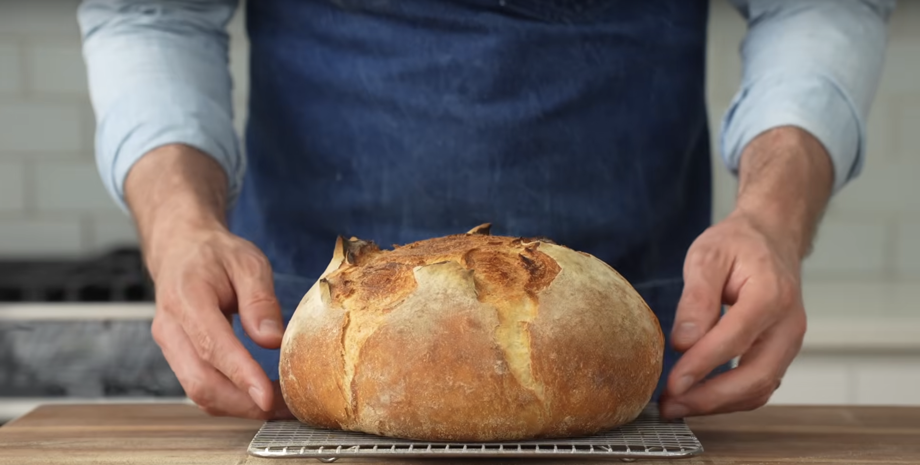 A screenshot showing standing behind a counter showing a loaf of bread.